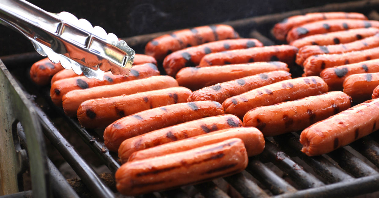 Hot dogs sizzling on a grill.