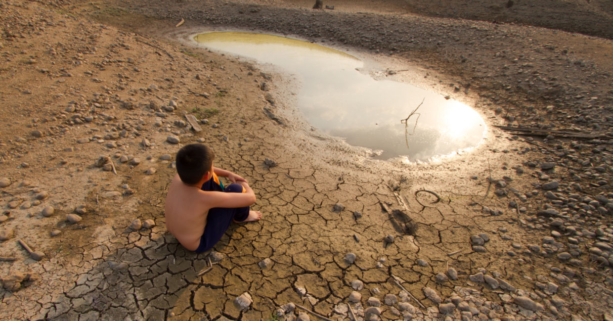 A child sitting near by a water source.