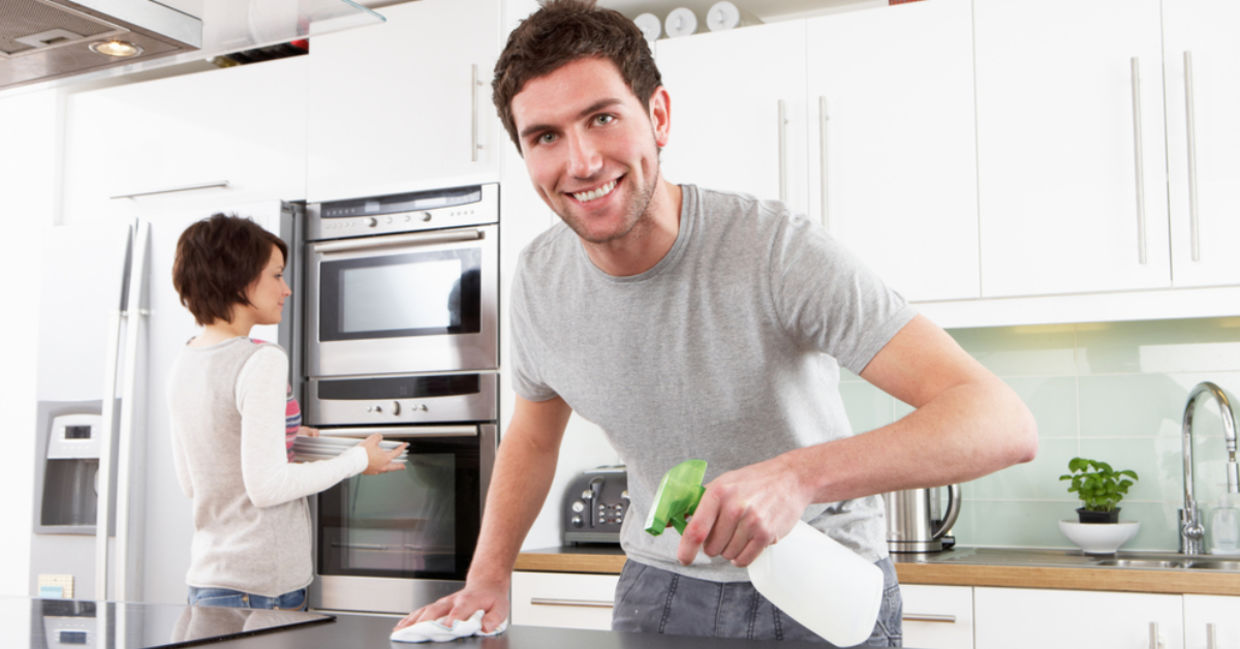 A man cleans his kitchen with a citric acid spray.