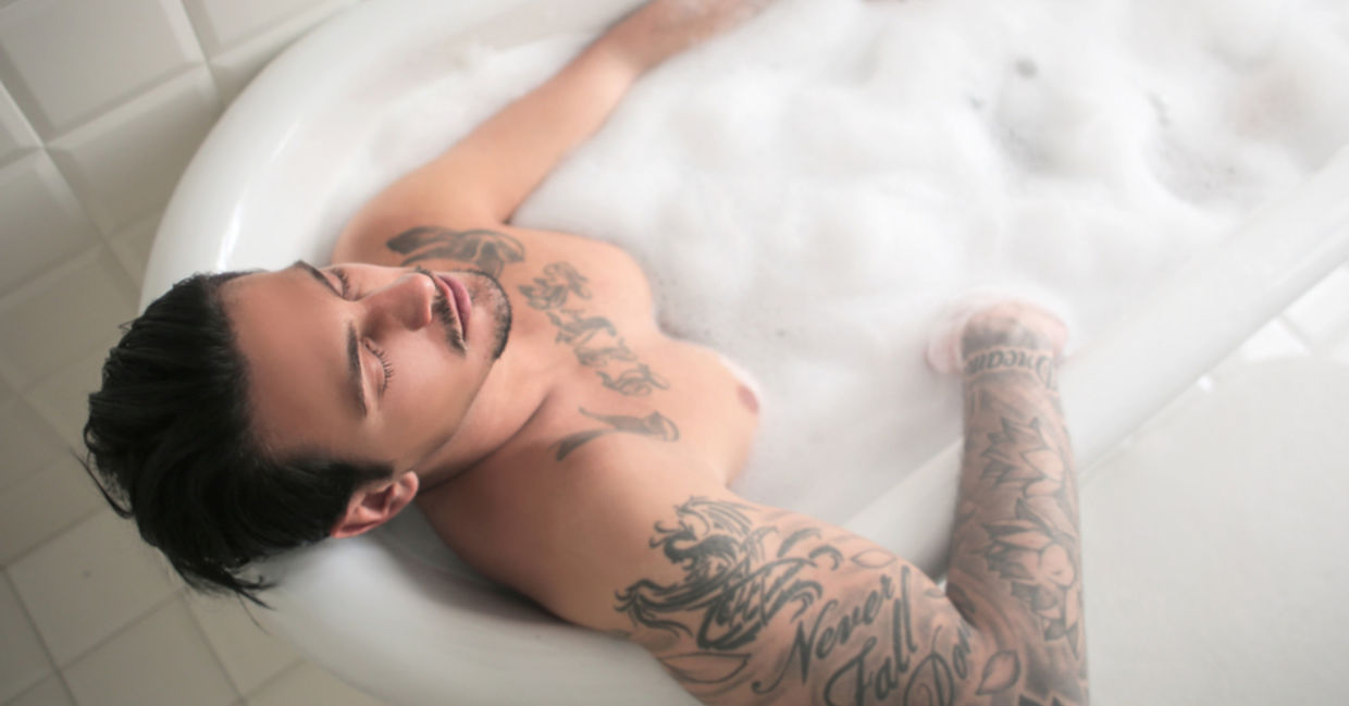 An athletic man soaks his muscles in a warm bath.