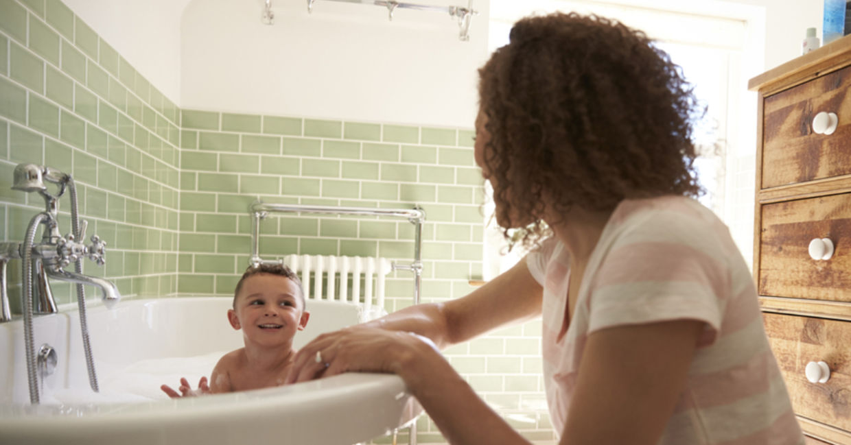 A mother helps bathe her toddler son.