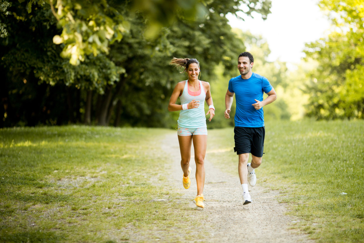 A young couple jogs in a park.