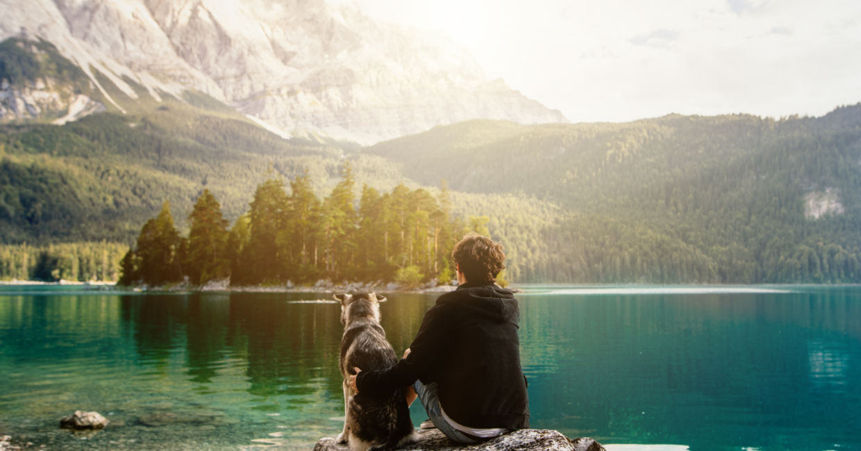 Man sitting with his dog in nature.