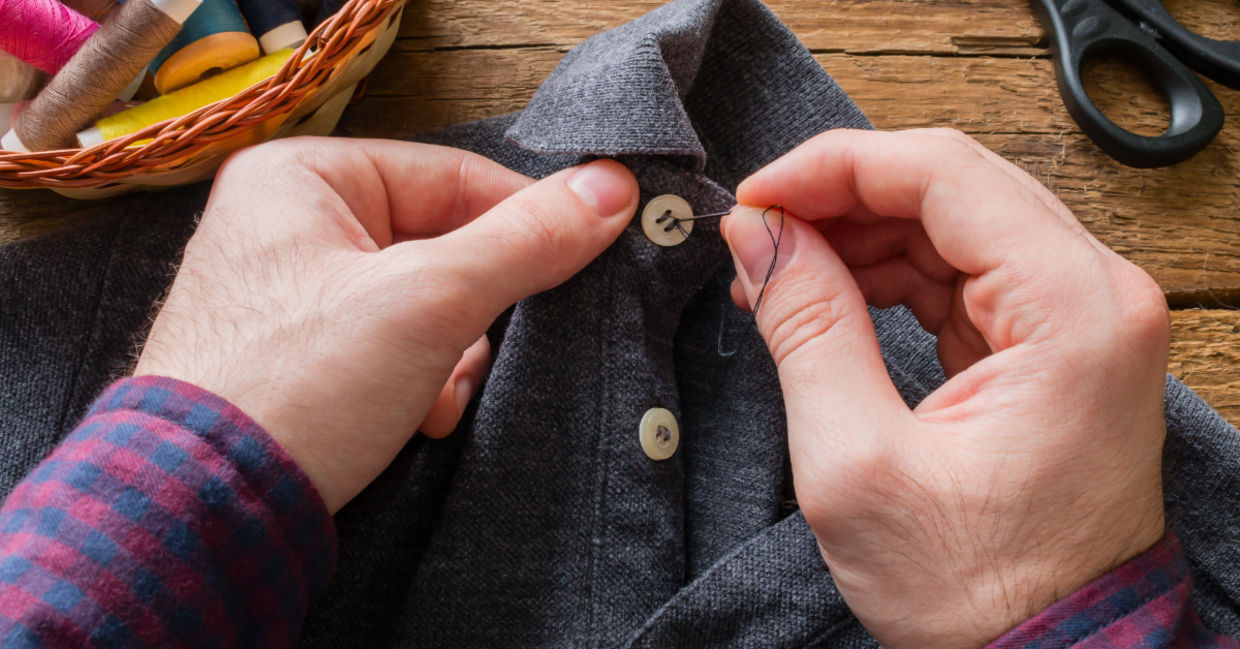 Main sewing a button on his shirt to make it last longer.