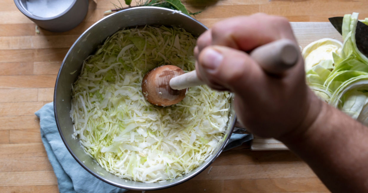 Making sauerkraut by tamping it down.