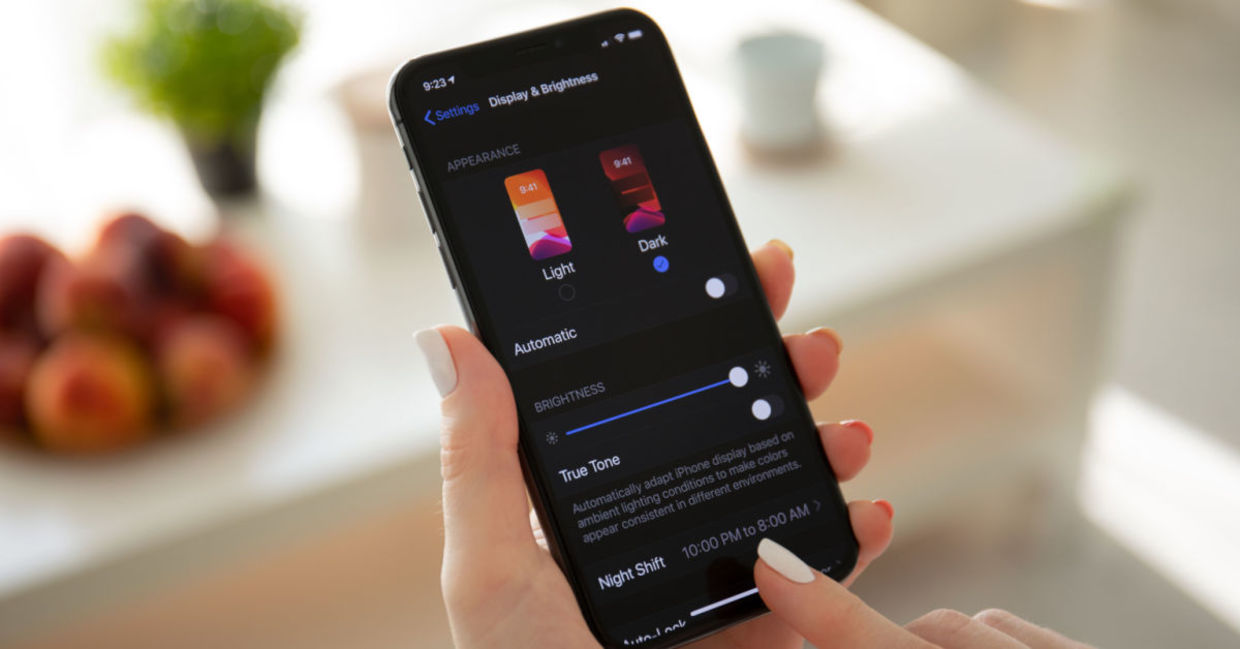 A woman looks at her smartphone in dark mode.