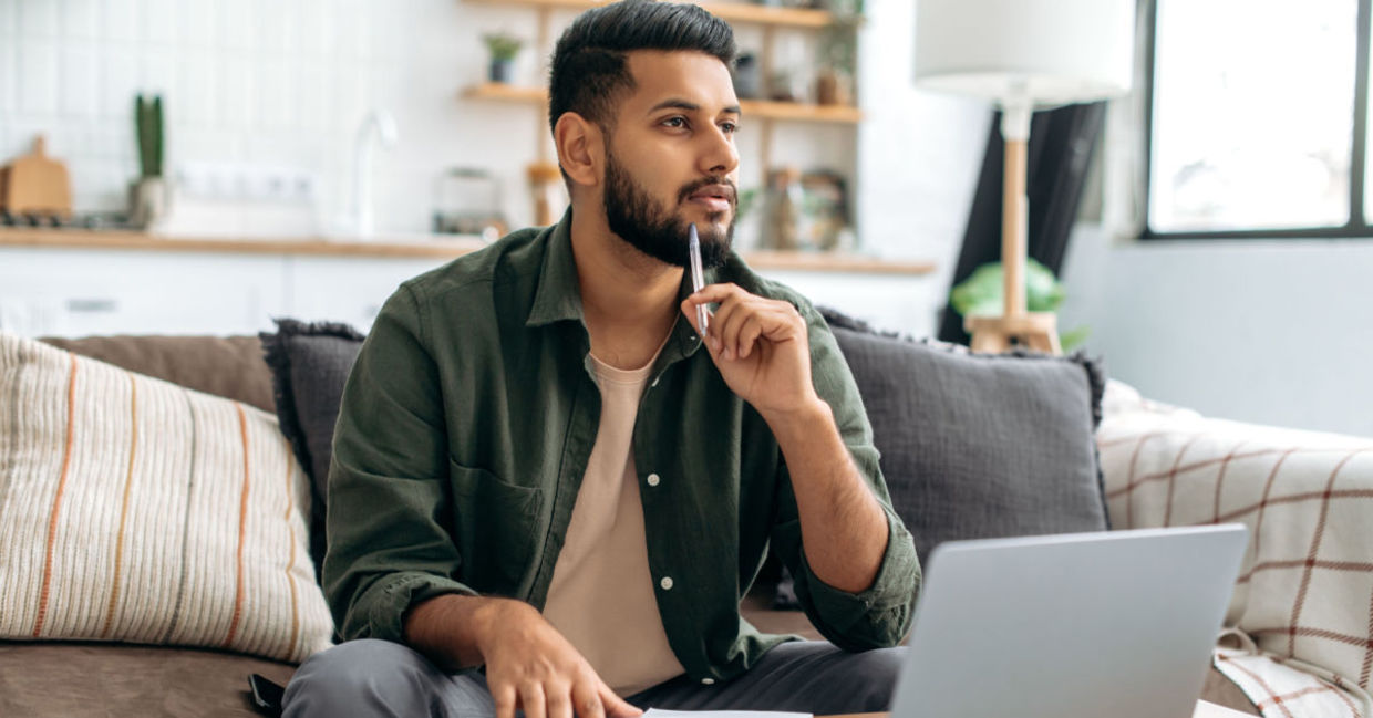 A man takes a break by looking away from his laptop.