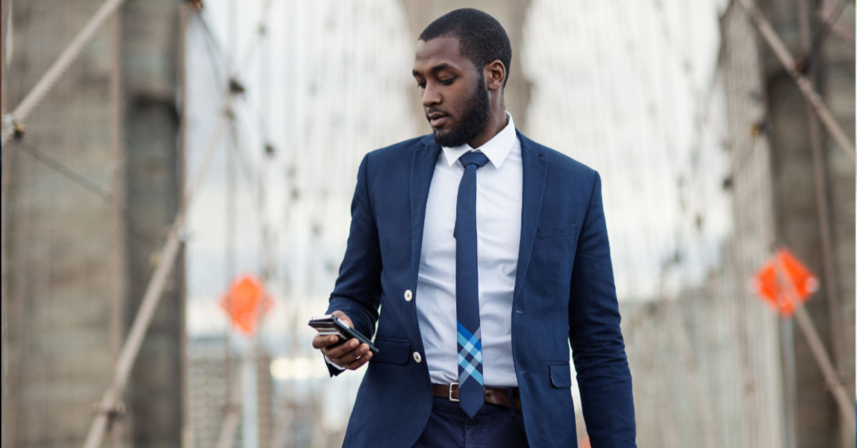 Young businessman using mobile phone on Brooklyn Bridge, New York City.