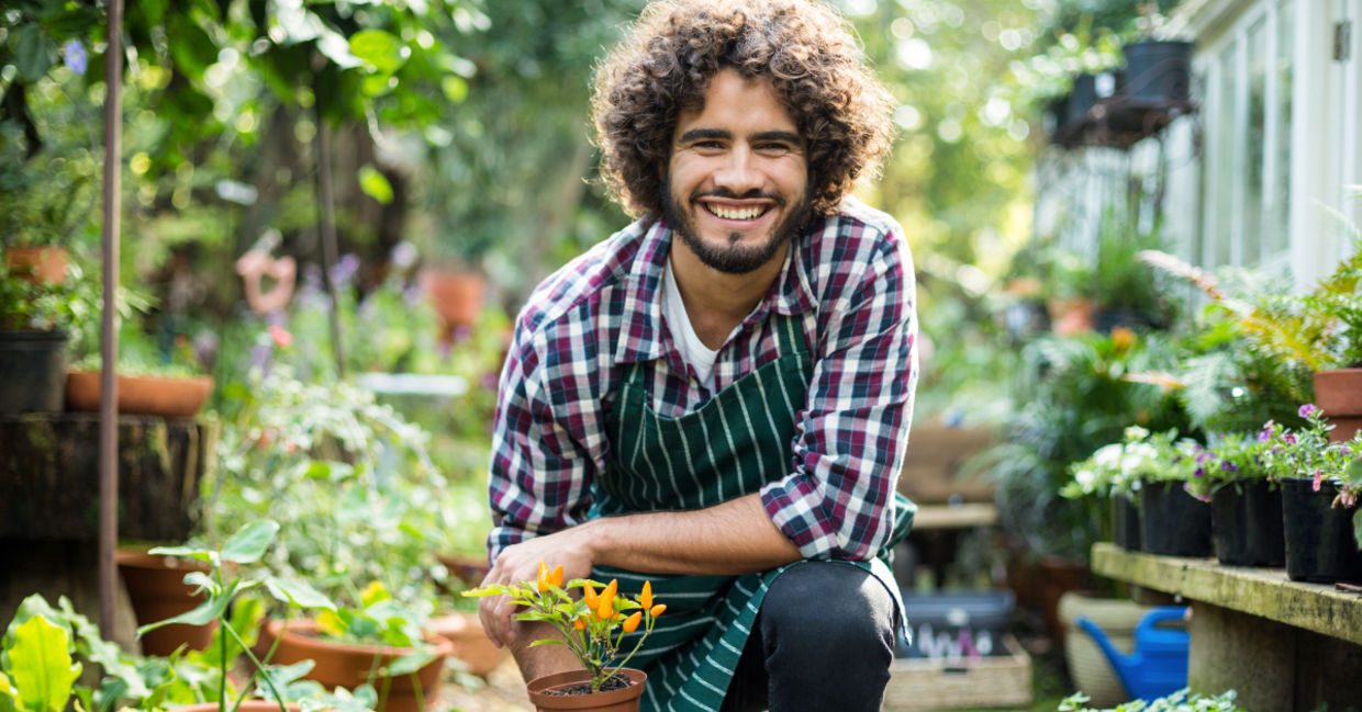 A smiling gardener with a plant.