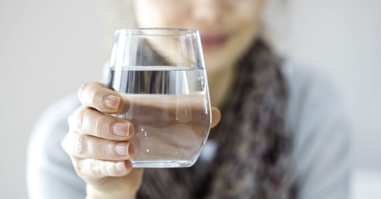 A young woman holding a glass of water.