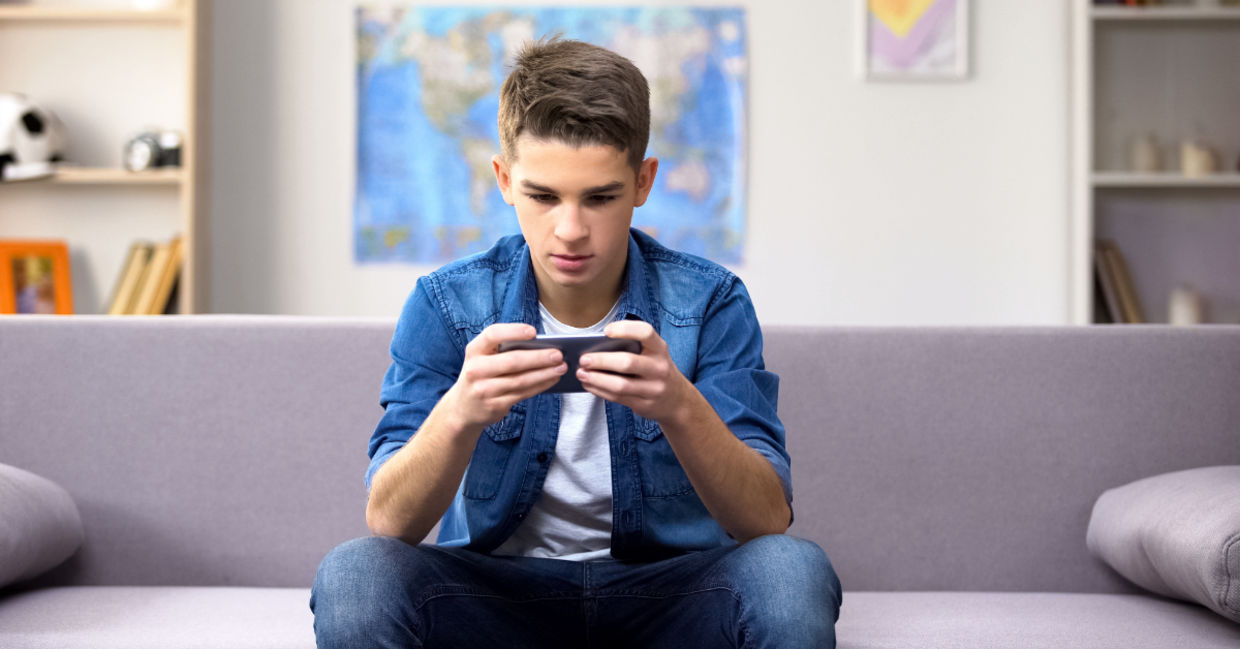 A teenager playing a game on his phone.