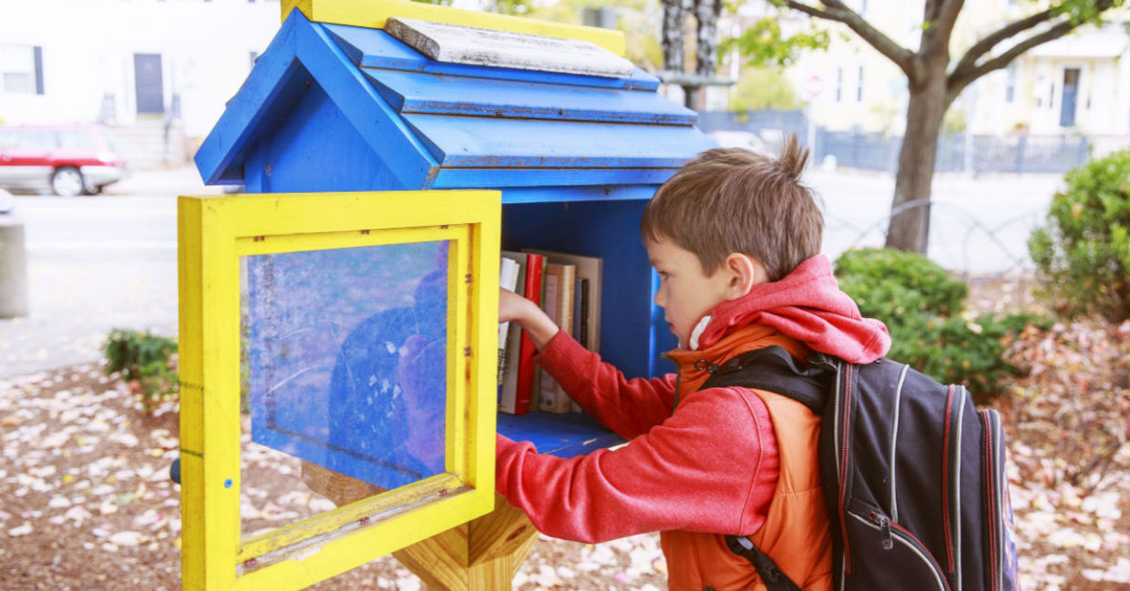 Child taking a book from a little street library.