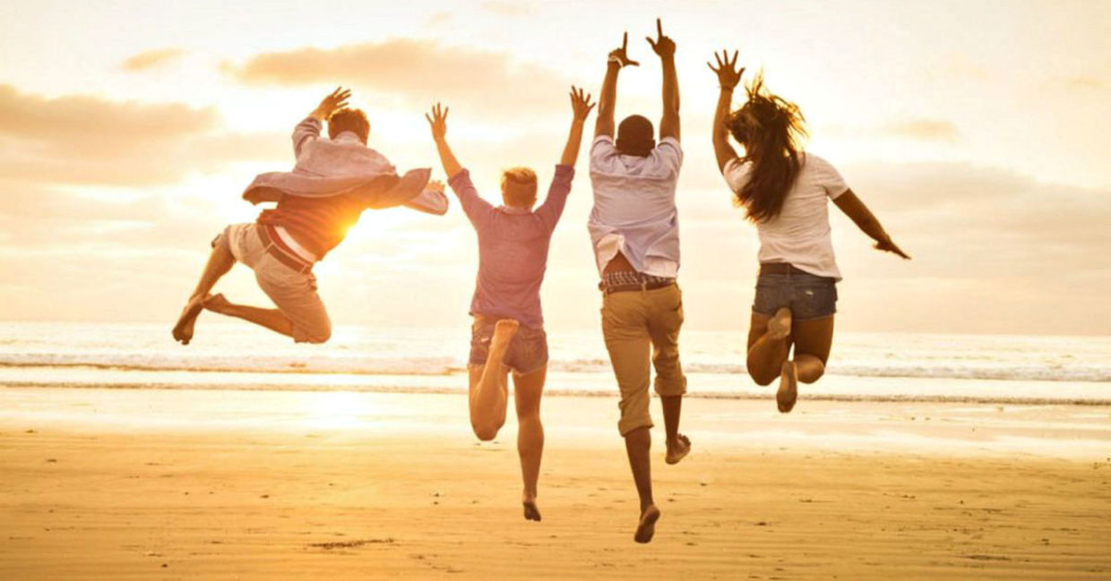 A group of friends jump for joy on the beach.