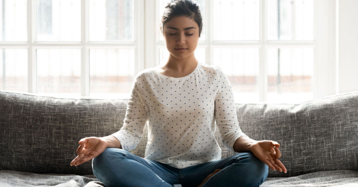 Mindful  young woman sitting in lotus position while engaged in mindful yoga practice.
