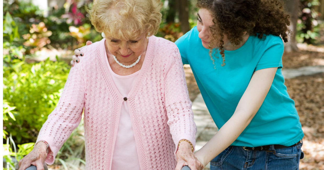 Teenage volunteer taking a walk with an older adult.