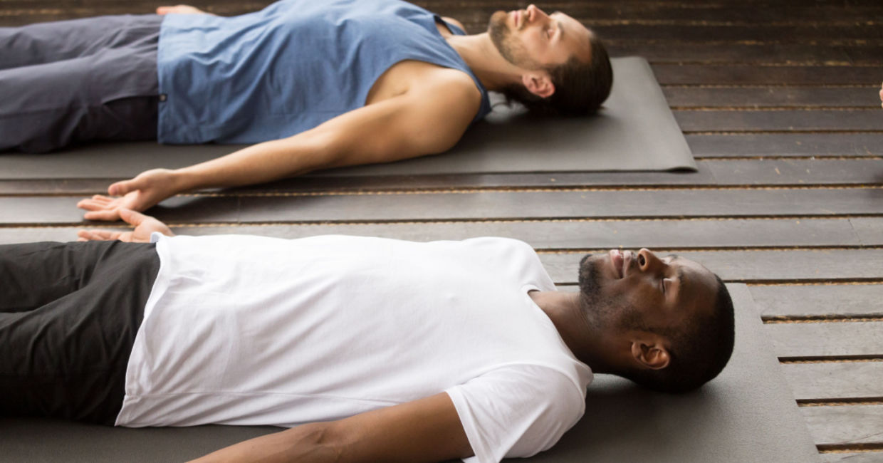 Men in the corpse pose during a yoga class.