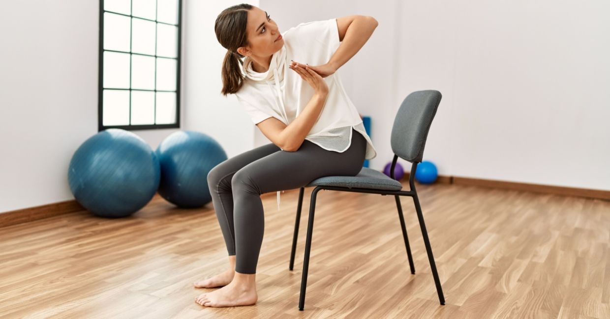 Woman performing chair yoga at a fitness center.