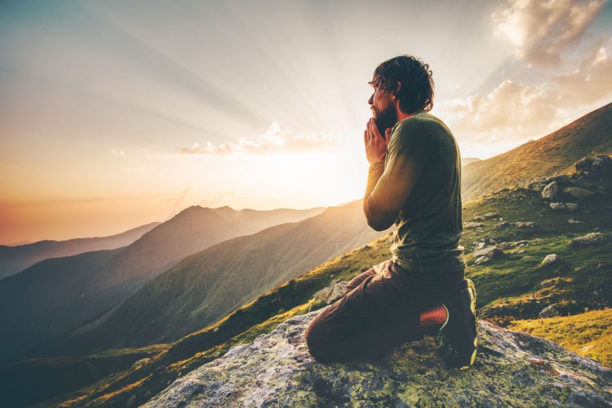 A man sits at sunset in the mountains.