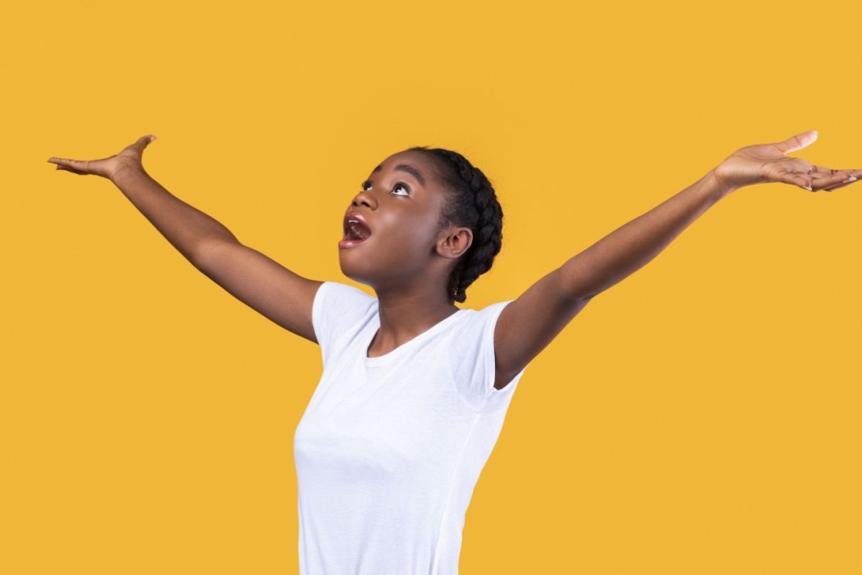 An amazed woman looks up with her hands raised.