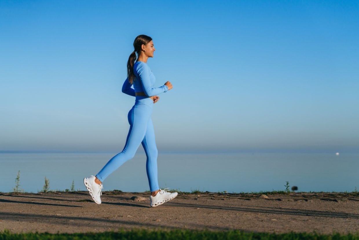 A woman walks along a waterside path.