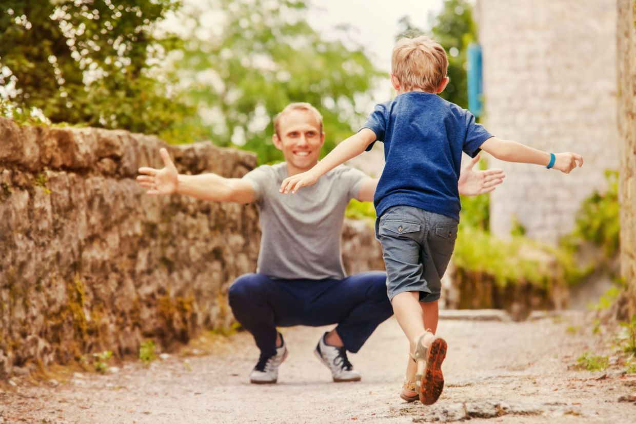A boy runs into his father’s arms.