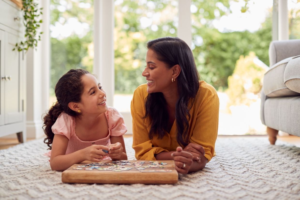 A mother and daughter lie on the floor at home.