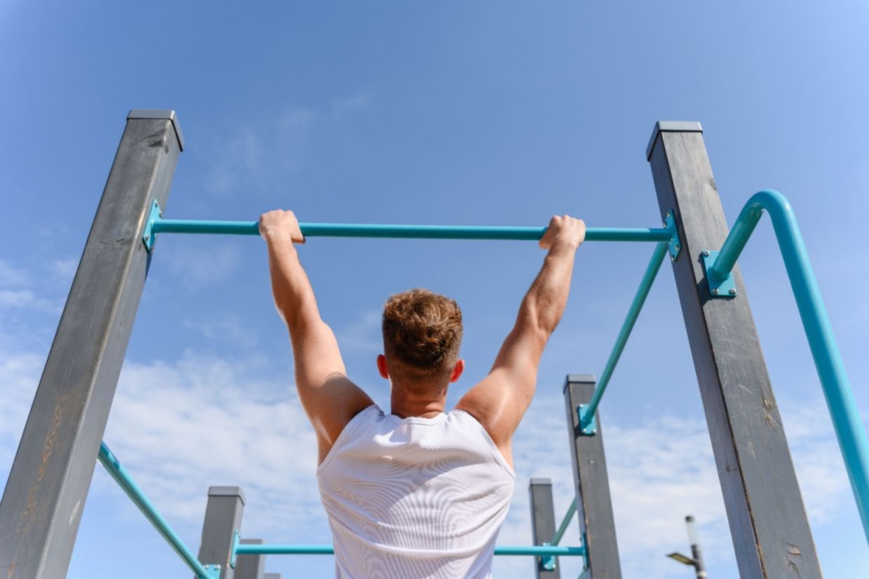 A man hangs from a bar.