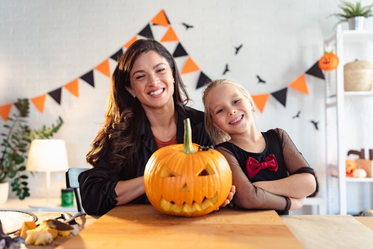 A mother and daughter proudly display their carved jack-o'-lantern.