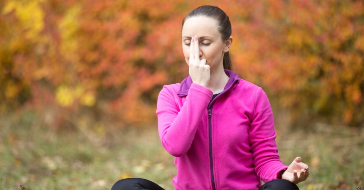 Woman practicing alternate nostril breathing.