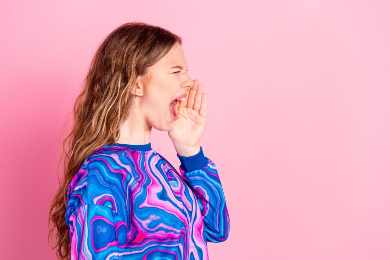 A young woman screams into an empty space.