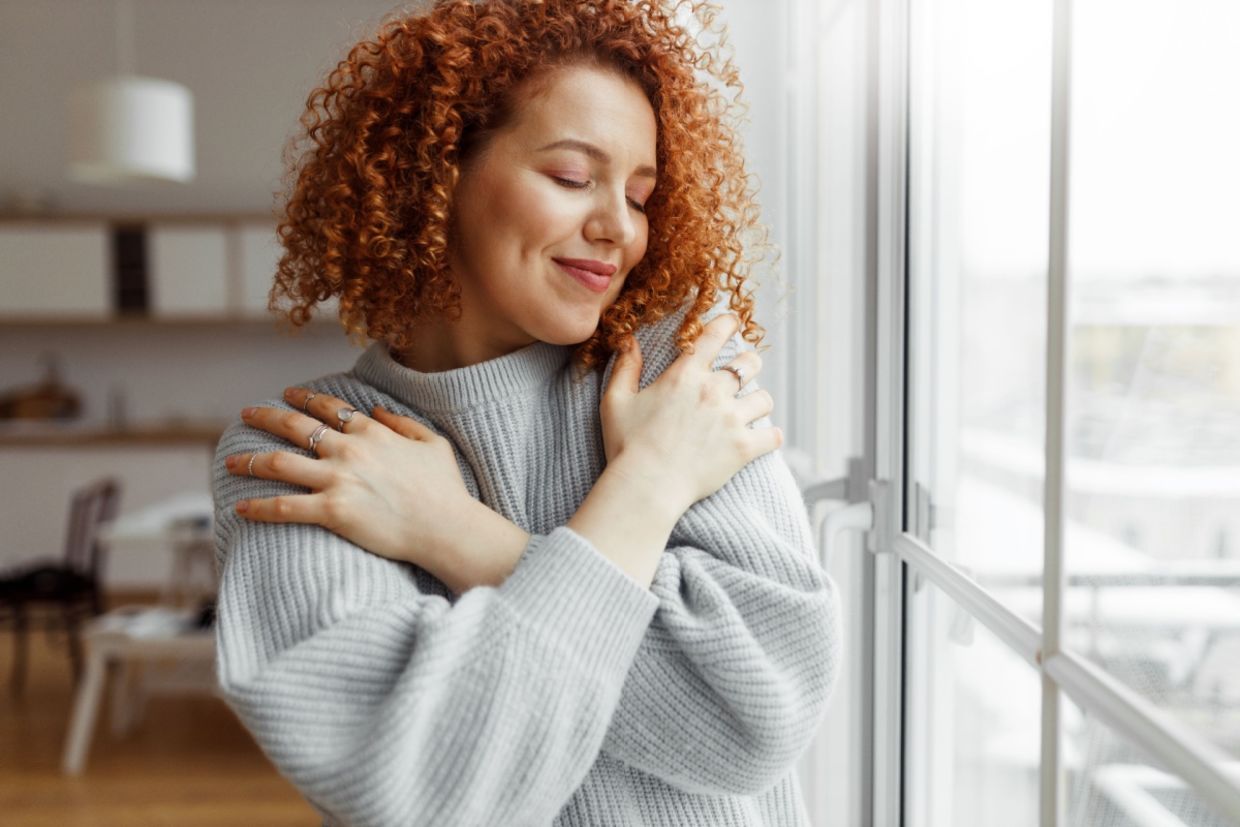 A woman hugs herself.