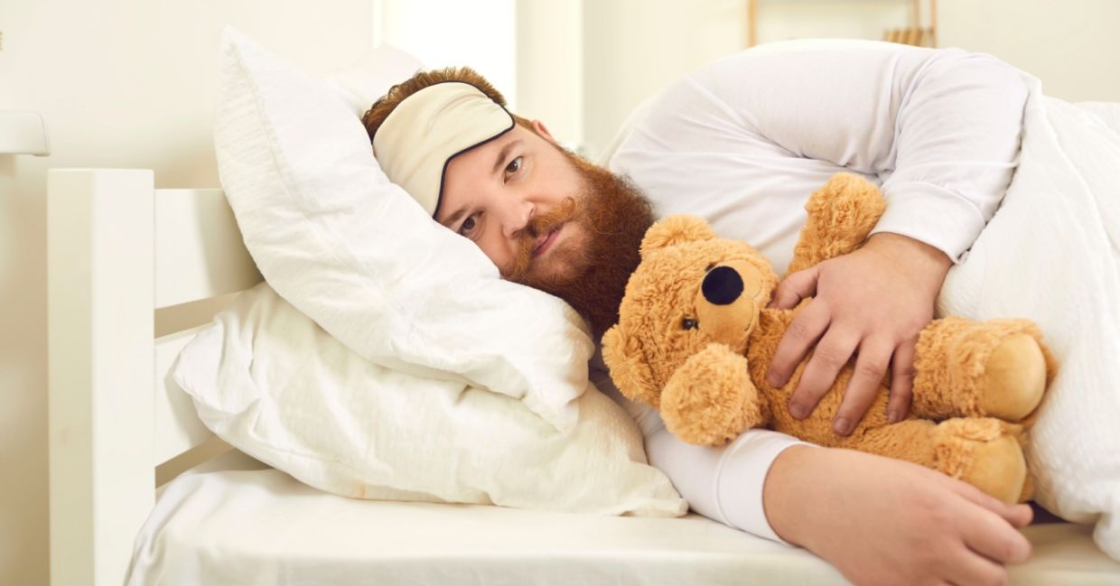 Adult man sleeping with a stuffed animal.