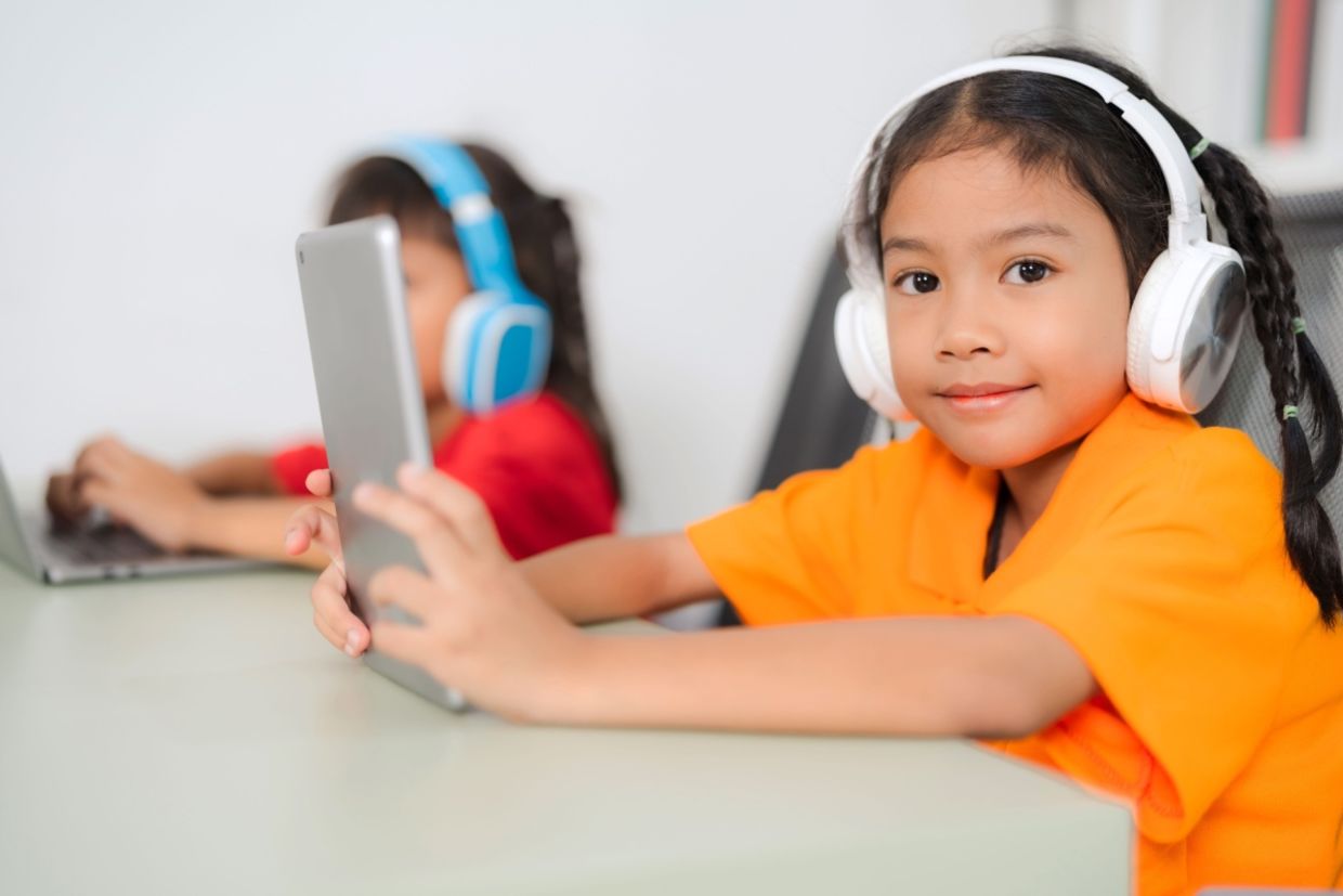 Two young students wear headphones.