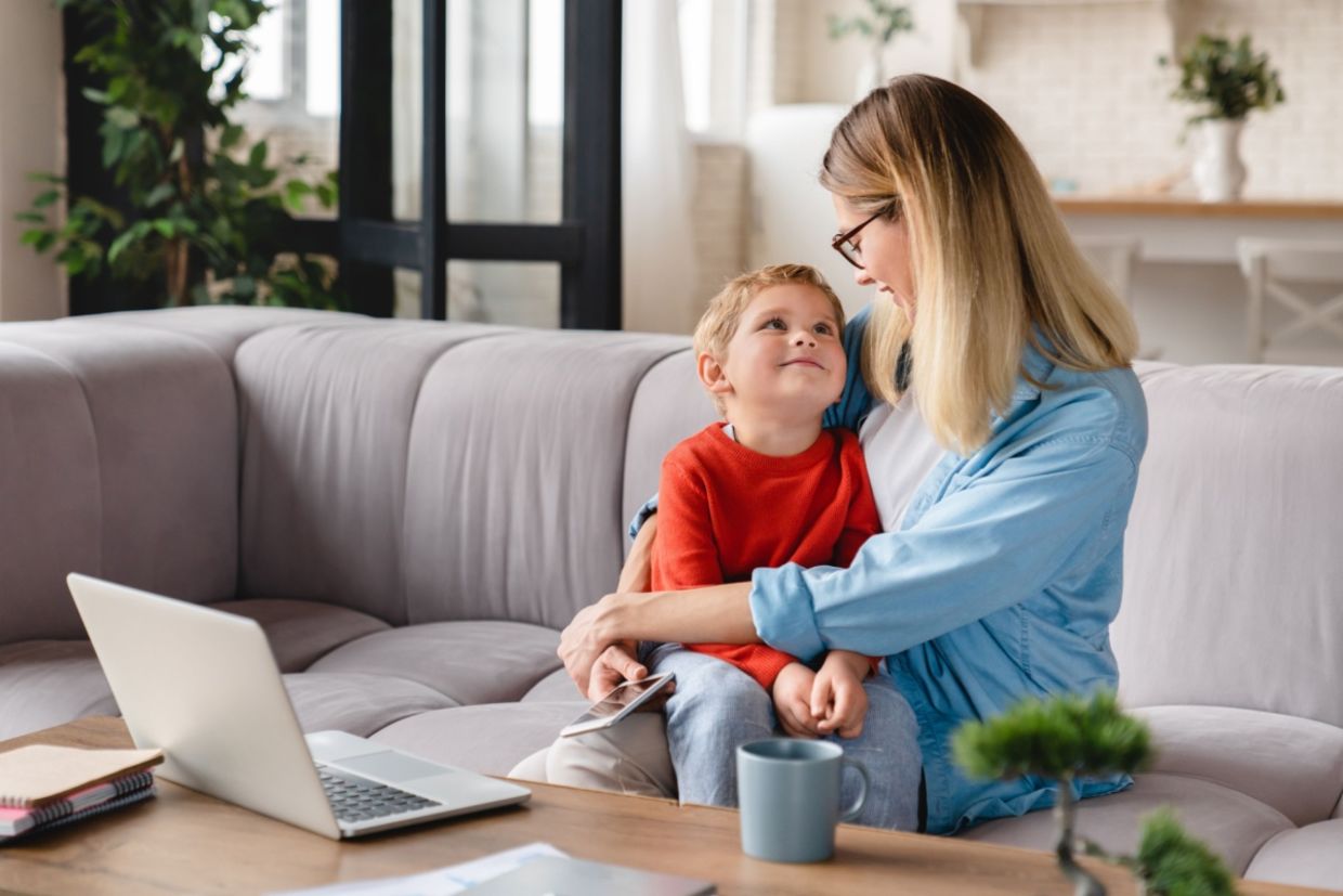 A mother and her child sit on a couch.