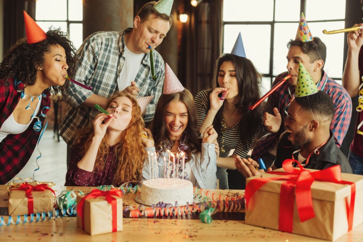 A group of friends celebrate together around a cake.