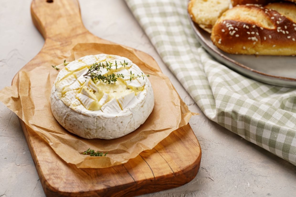 Oven baked camembert cheese on wooden board.