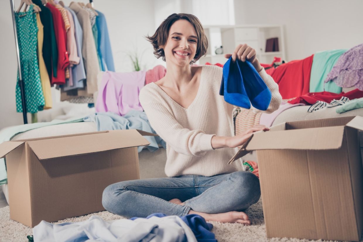 A woman holds up a pair of shoes.