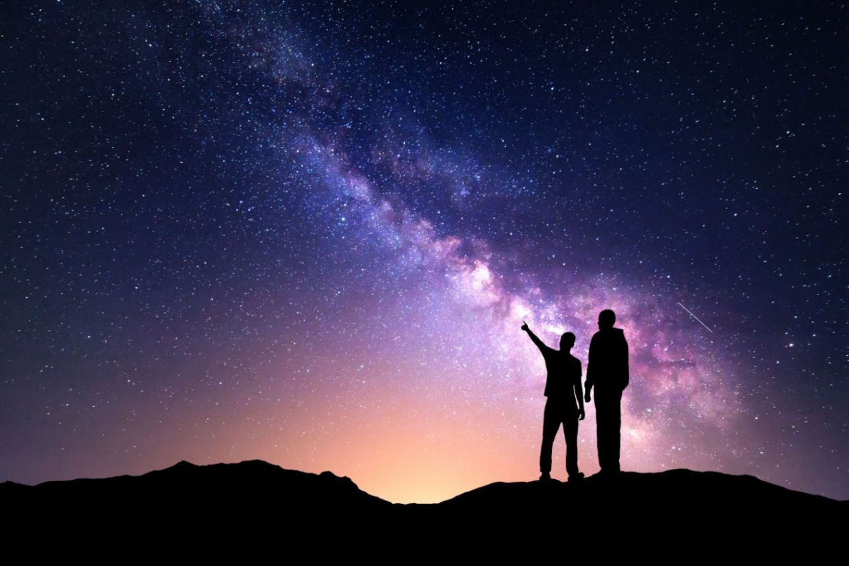 A silhouette of a family with a backdrop of the milky way.