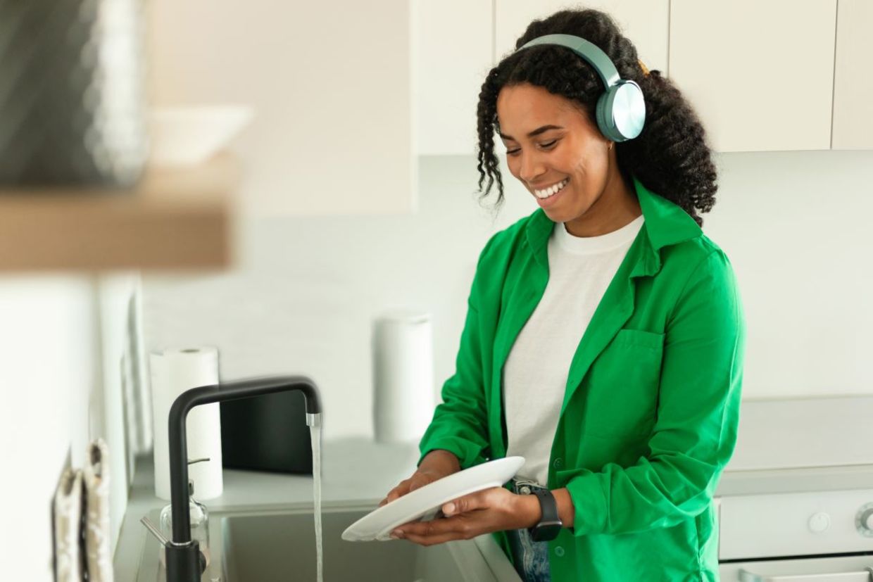 Woman listening to an audiobook while doing dishes. Woman listening to an audiobook while doing dishes.