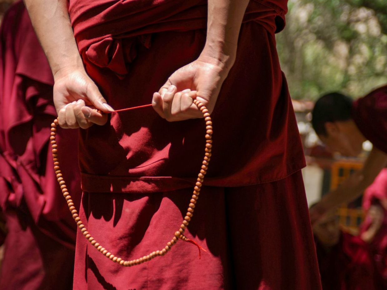 Tibetan Buddhist Monk with his red robe and prayer beads.
