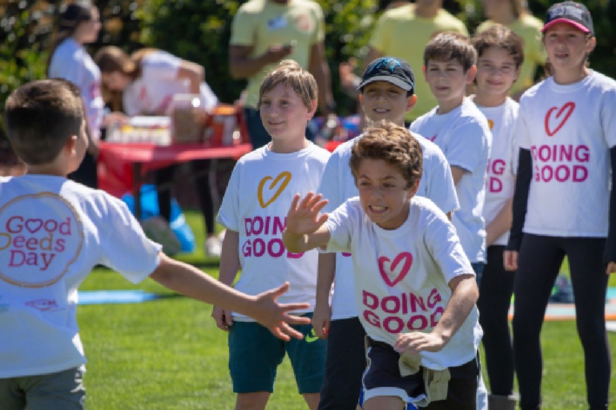 Children wearing “Doing Good” shirts run and play together at a community event.