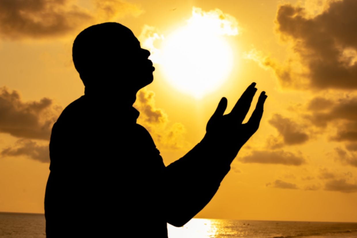 A man silhouetted against a colorful sunset.