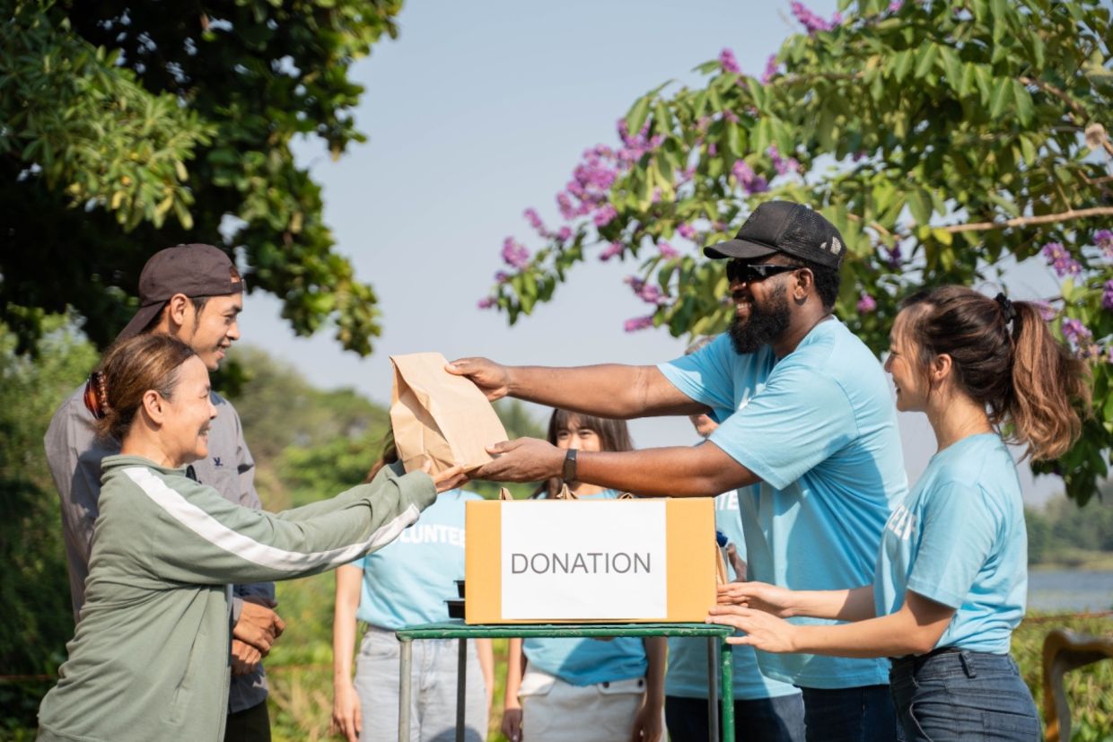 A team of volunteers with a donation box outdoors.