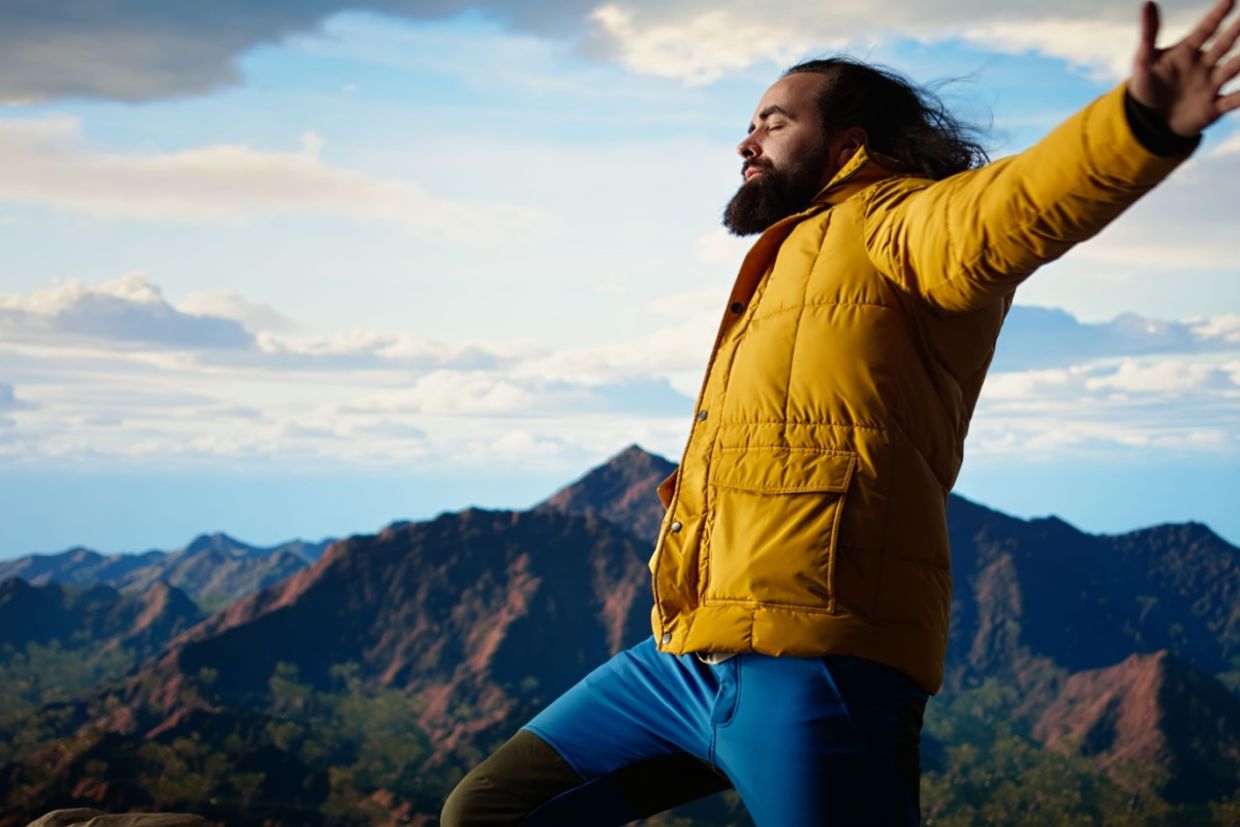 A happy adventurer standing at the top of a mountain.