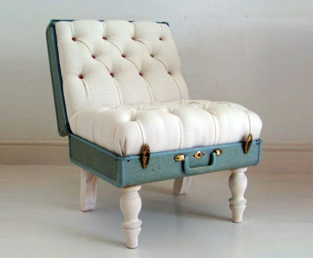 Chair made from a vintage blue suitcase with cream tufted cushioning and white painted wooden legs.
