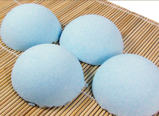 Aromatherapy. Four round blue bath bombs arranged on a bamboo mat, viewed from above.