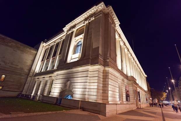 Imperial Imperial College at night, Classical stone building with columns illuminated by warm lighting at night against a dark sky.