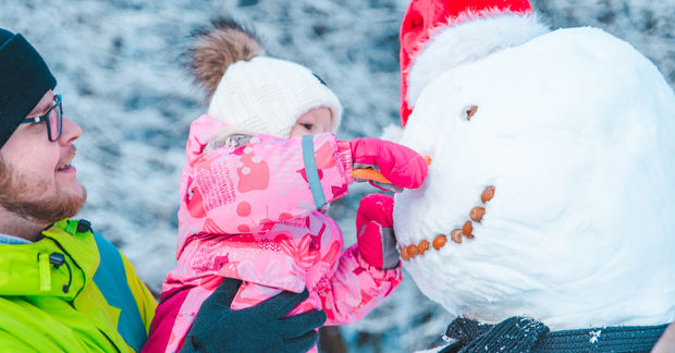 photo Father and child building snowman outdoors.