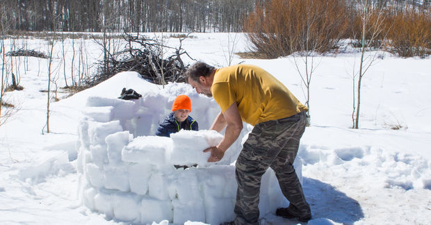 photo Father and child building snow fort outdoors.