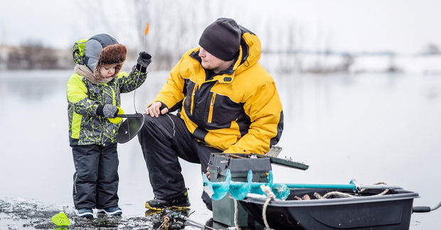 photo Father and child ice fishing on frozen lake.